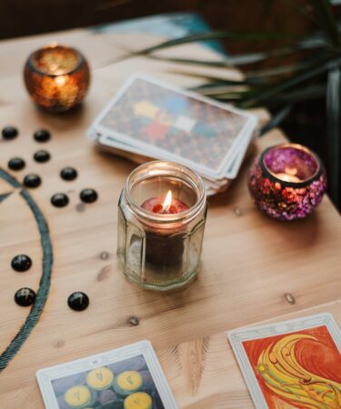 burning candles near tarot cards on table